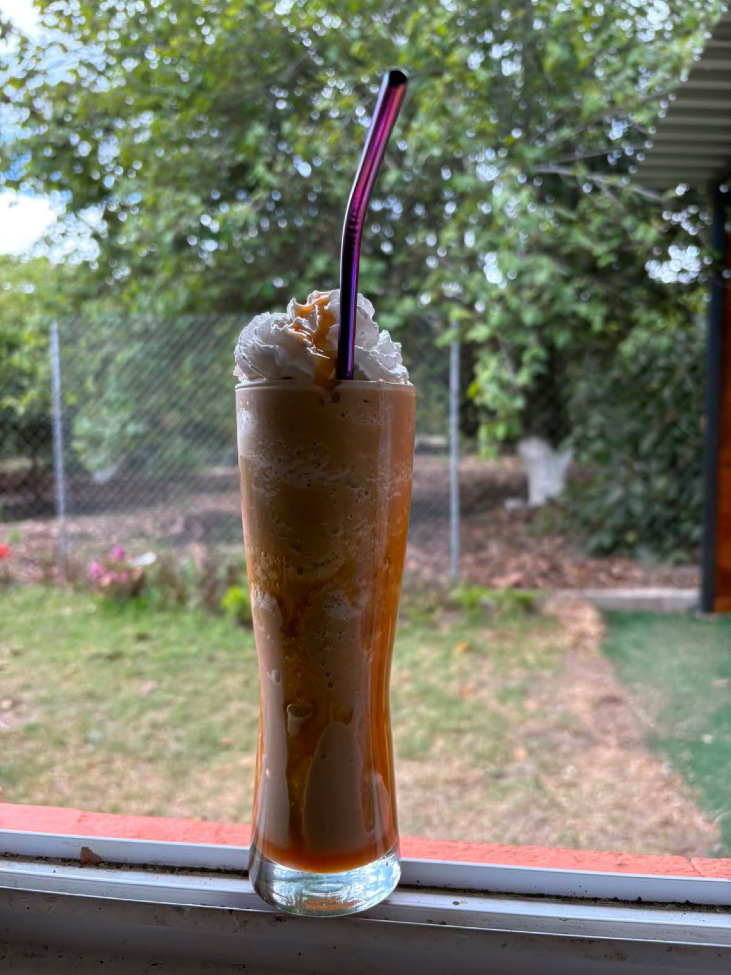 Frappe de caramelo con crema y pitillo morado